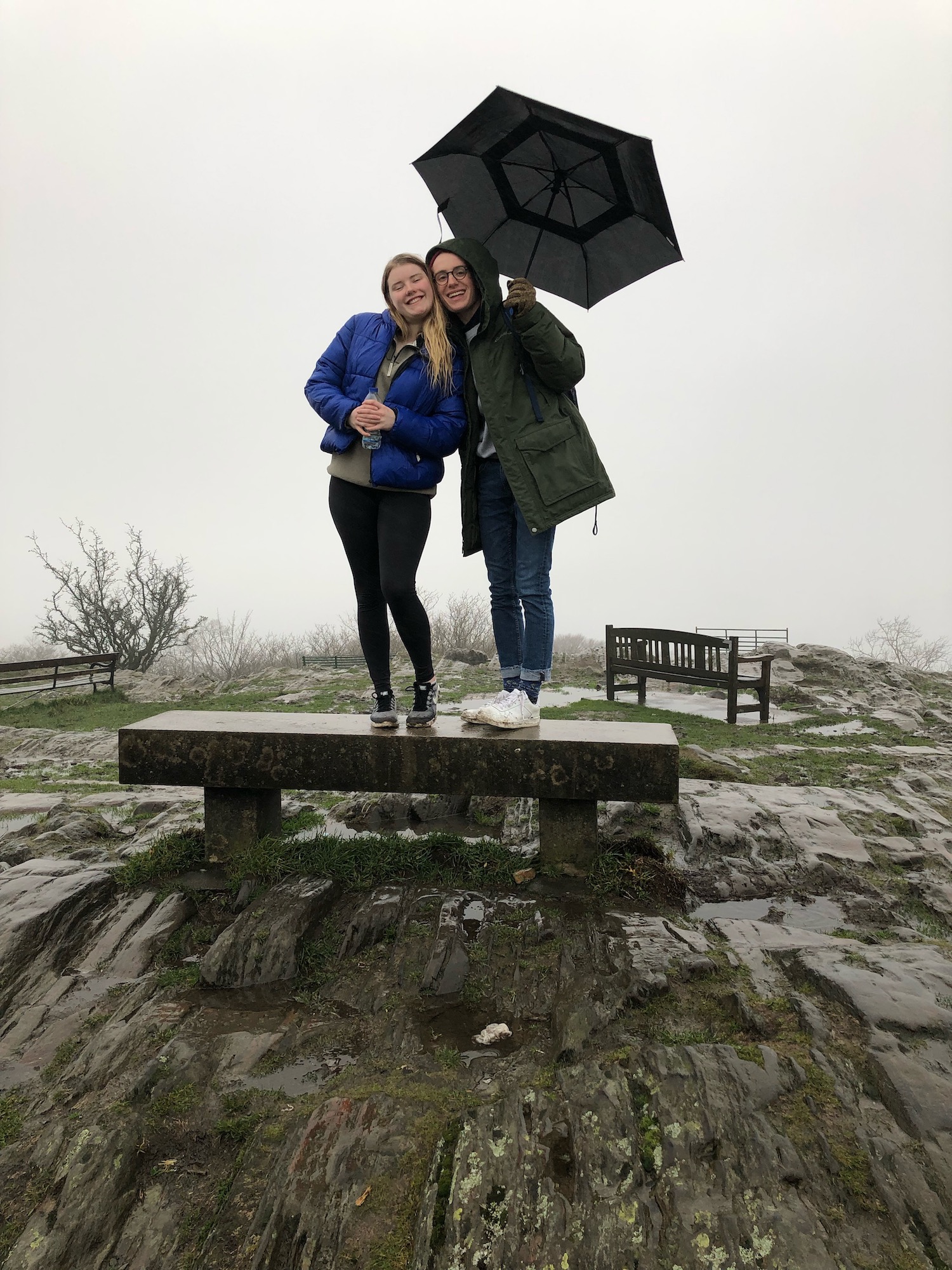 students standing on bench with umbrella